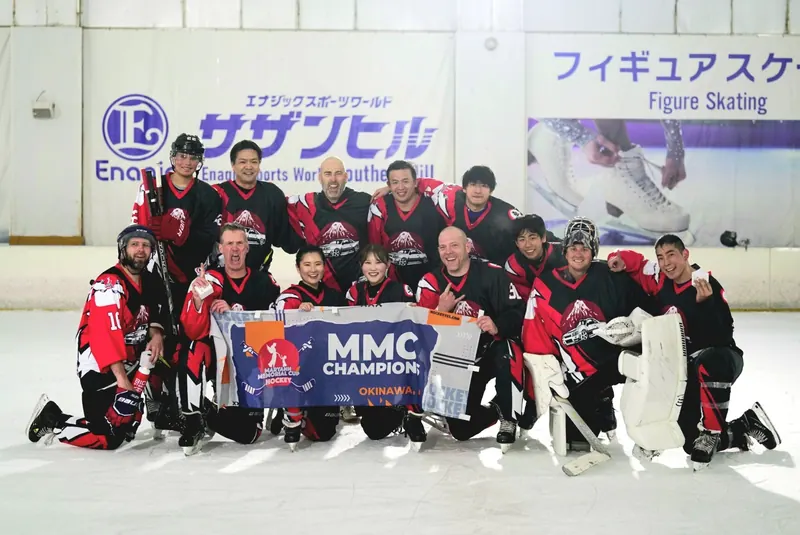 The 2025 champions posing on the ice with the MMC champion banner